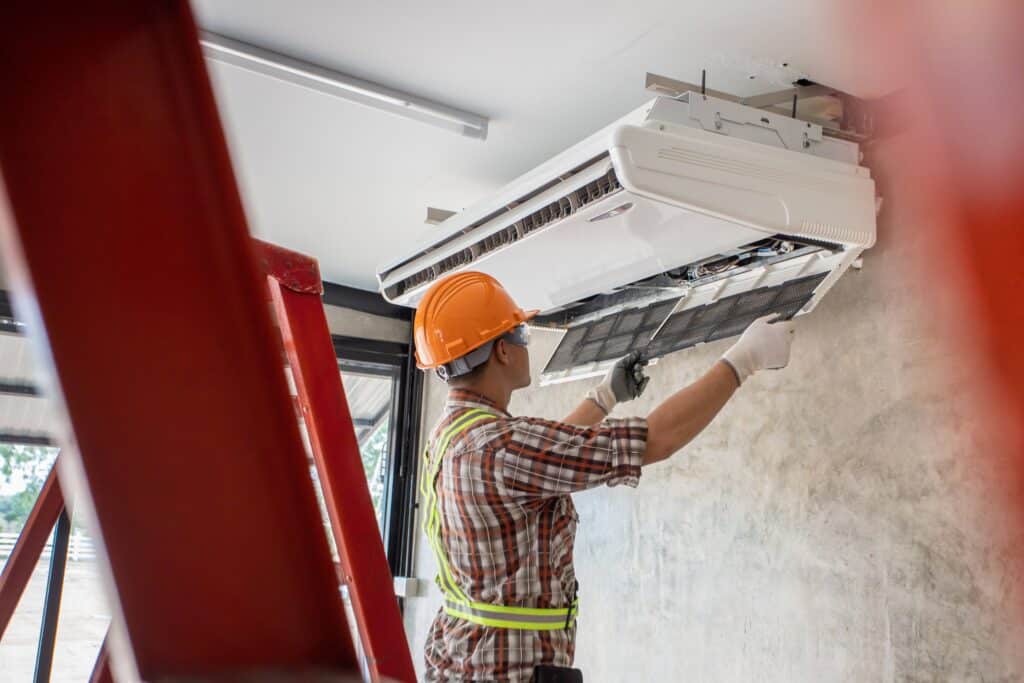 Un technicien qui installe un climatiseur mural dans le salon d’une maison